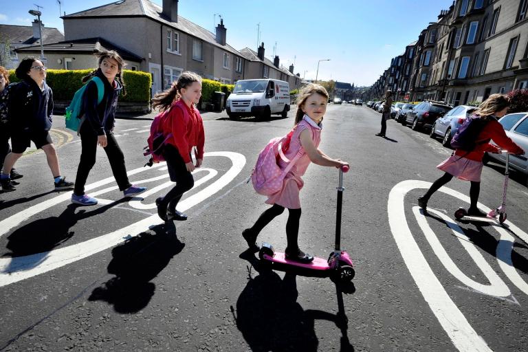 Children wheeling and walking across the road.