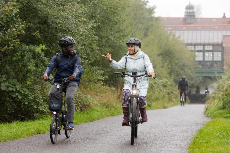 Two cyclists on a cycle path wearing helmets.