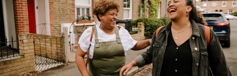 Two women walking near housing, unknown location